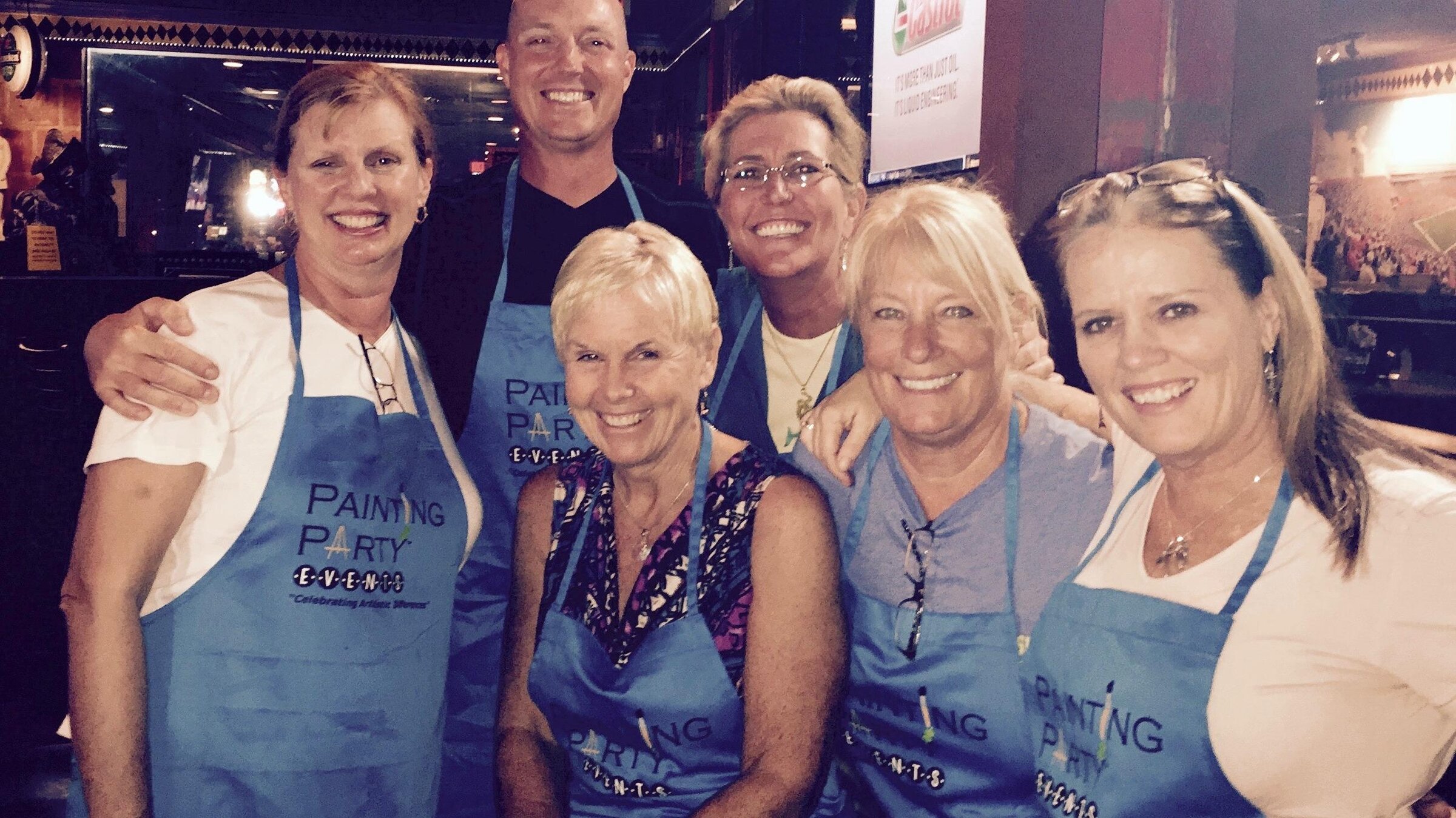 Guests in Painting Party Events aprons at a restaurant painting event.