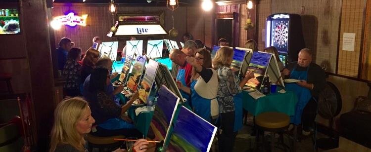 Guests seated together painting inside a restaurant bar during a Painting Party Events night.