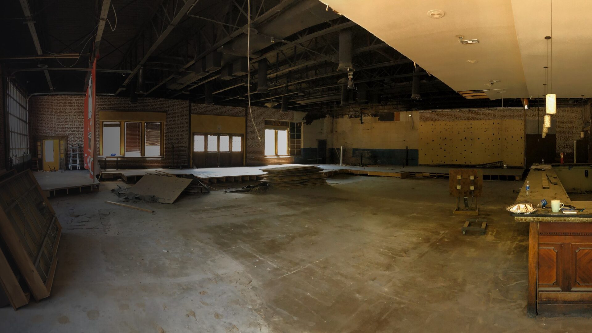 The raw, unfinished interior space before construction — exposed brick, bare concrete, and no stage.